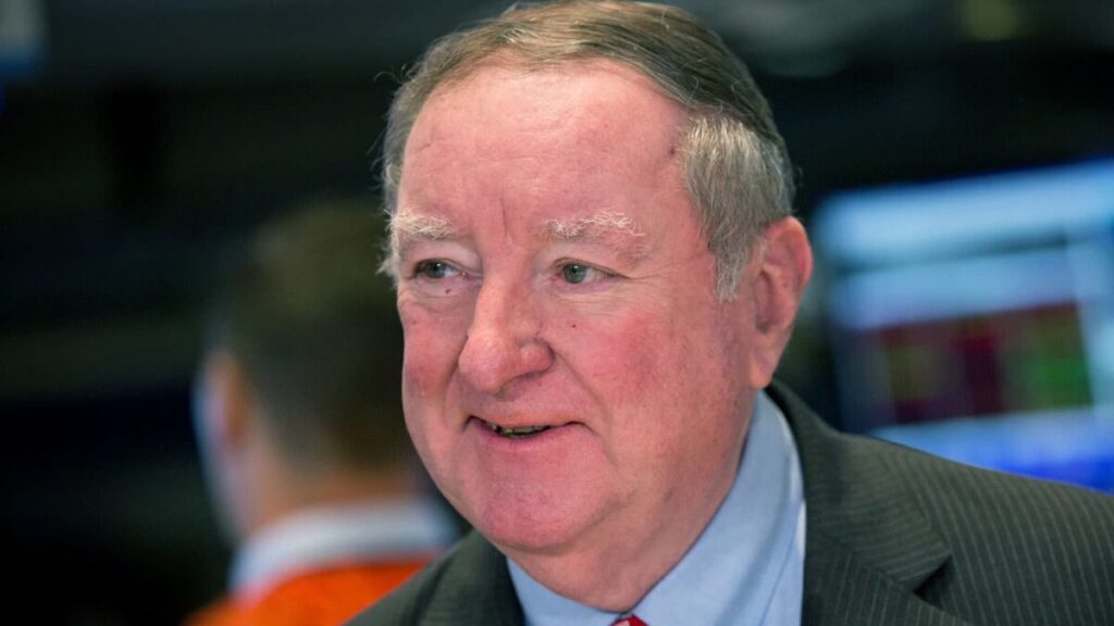 Art Cashin smiling on the New York Stock Exchange floor, wearing his signature Irish sweater — a glimpse into the personal charm and humility behind the Wall Street legend.