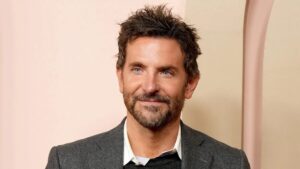 Bradley Cooper smiling at a event, wearing a classic suit.