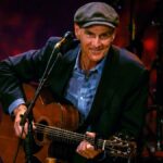 James Taylor performing live on stage with guitar