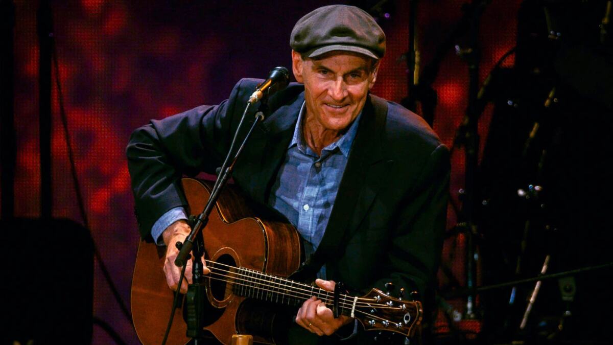 James Taylor performing live on stage with guitar
