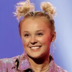 JoJo Siwa smiling in a colorful outfit with her signature hair bow