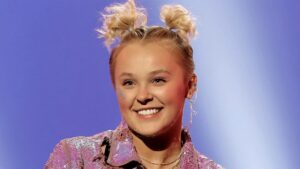JoJo Siwa smiling in a colorful outfit with her signature hair bow