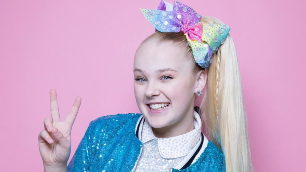 JoJo Siwa performing on stage during her D.R.E.A.M. Tour, wearing a colorful outfit with her signature bow – representing a major milestone in her music and entertainment career.