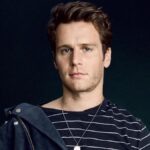Jonathan Groff posing during a professional photo shoot, wearing a stylish outfit