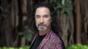 Marco Antonio Solís posing in a formal suit during a music awards ceremony.