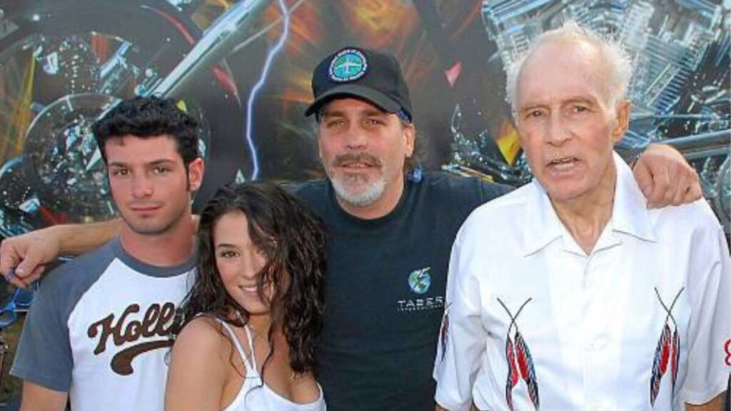 Robbie Knievel standing beside his father Evel Knievel and his daughters, showcasing three generations of the Knievel family