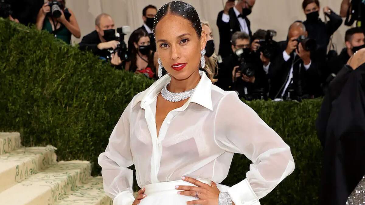 Alicia Keys on the red carpet at the 2025 GRAMMY Awards, posing for media photographers in a shimmering black gown.