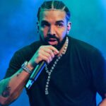 Drake performing live on stage wearing a black t-shirt during a concert.