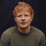 Ed Sheeran posing during a professional photo shoot, wearing casual attire with a neutral background.