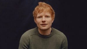 Ed Sheeran posing during a professional photo shoot, wearing casual attire with a neutral background.