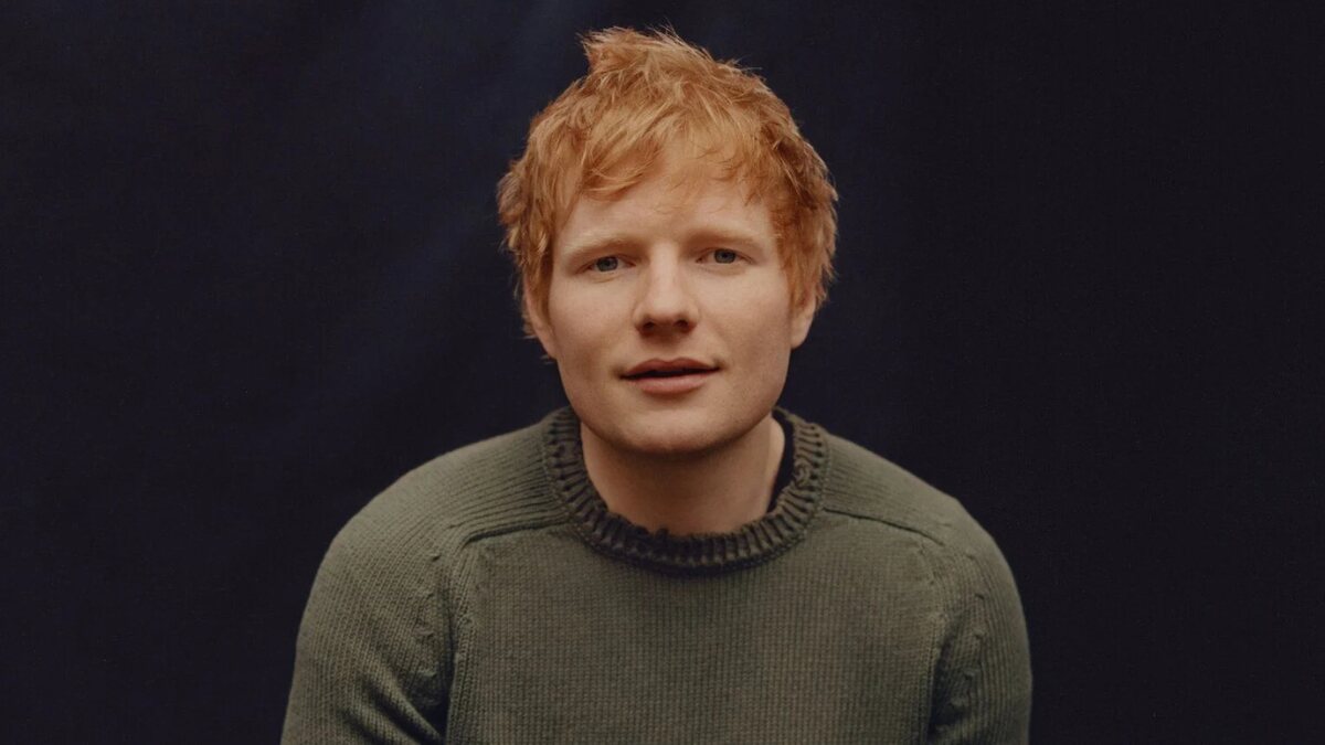Ed Sheeran posing during a professional photo shoot, wearing casual attire with a neutral background.