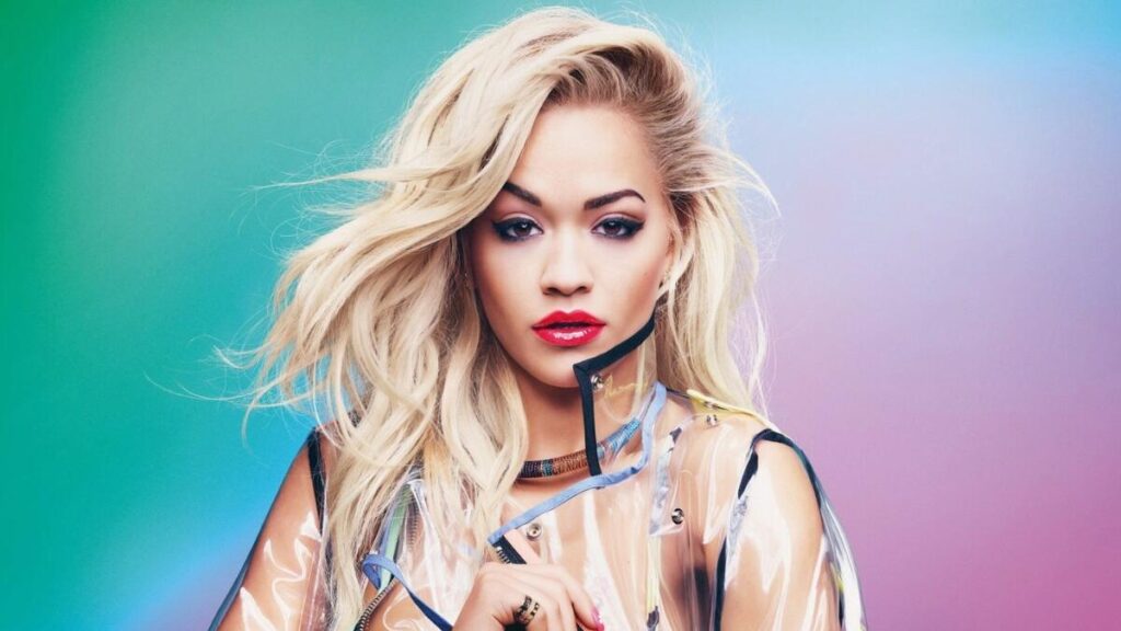 Rita Ora posing in a high-fashion outfit during a professional photo shoot, showcasing her signature glam style.