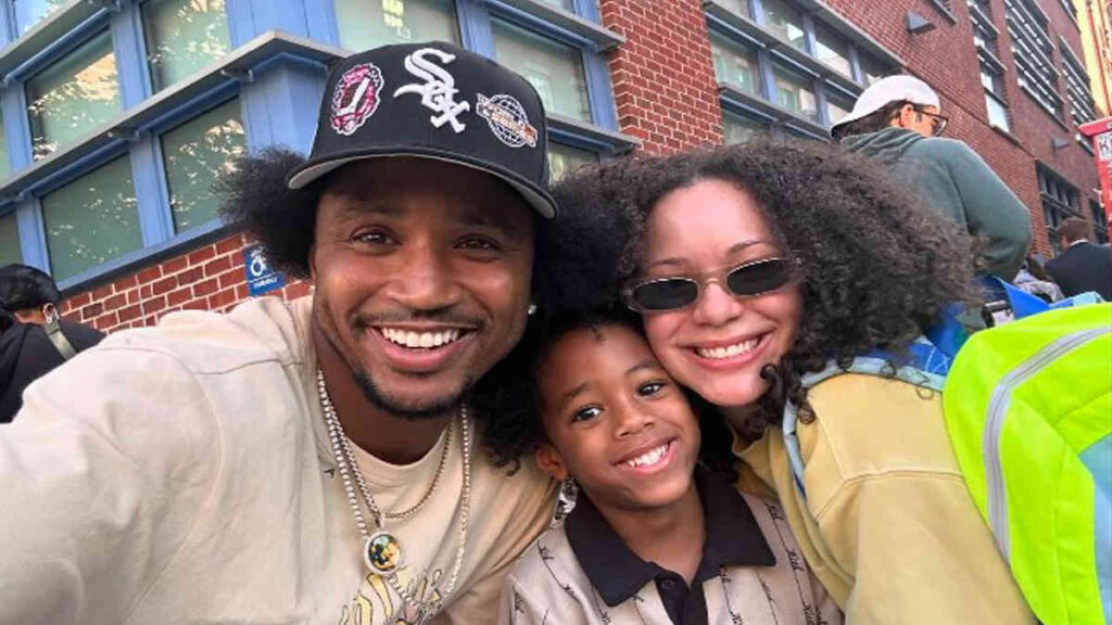 Trey Songz walking with Caro Colon and their son Noah on a city street, dressed casually in streetwear.