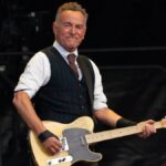 Bruce Springsteen singing during a concert with spotlight and crowd
