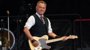 Bruce Springsteen singing during a concert with spotlight and crowd