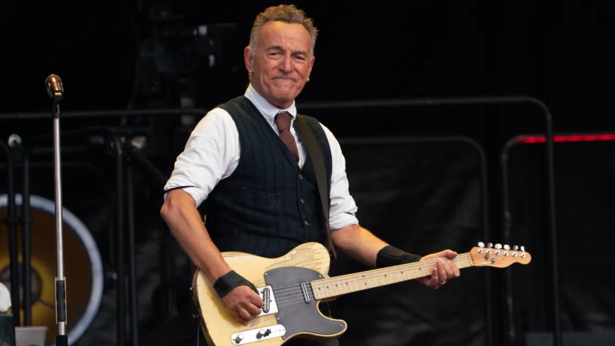 Bruce Springsteen singing during a concert with spotlight and crowd