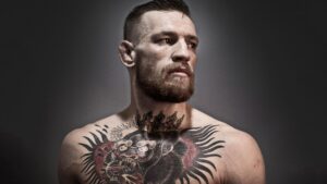 Conor McGregor is posing confidently during a professional photo shoot, showcasing his luxury fashion style and bold persona.