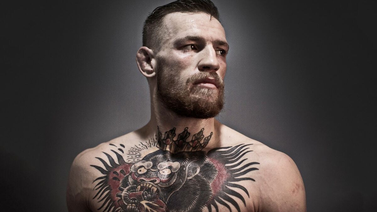 Conor McGregor is posing confidently during a professional photo shoot, showcasing his luxury fashion style and bold persona.