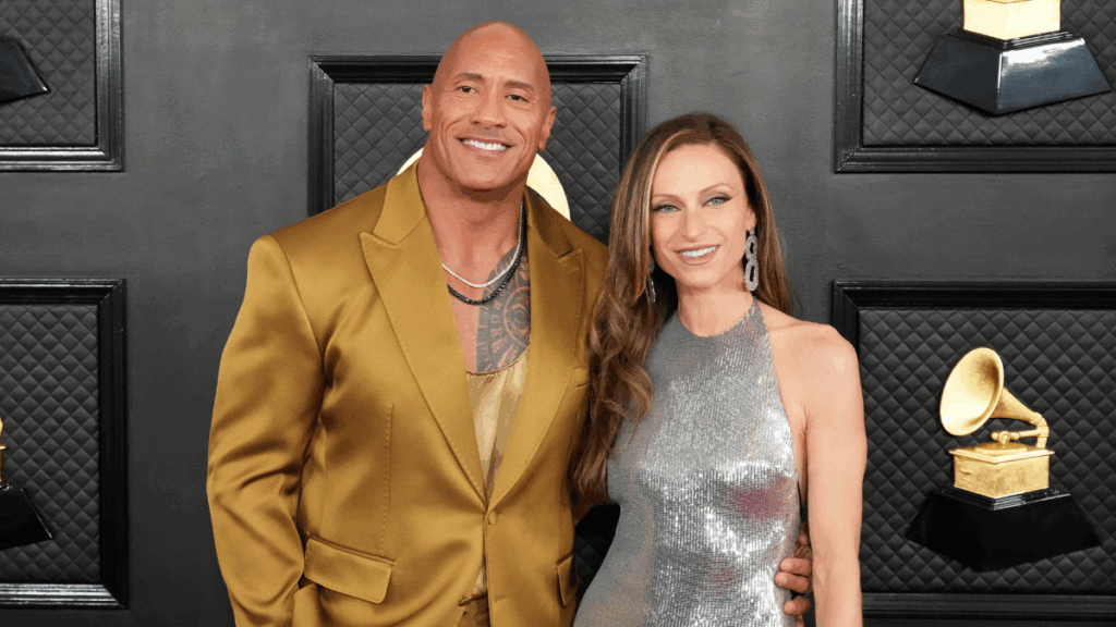 Dwayne “The Rock” Johnson and wife Lauren Hashian posing together on the red carpet at an award show, dressed in formal attire and smiling for the cameras.