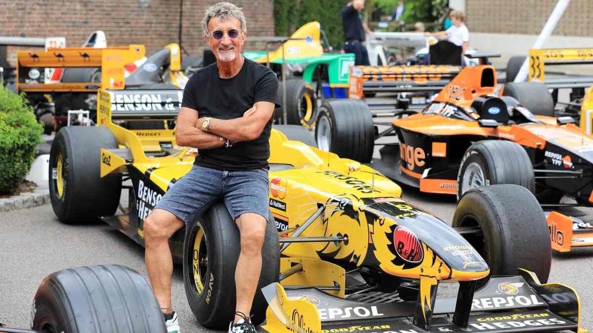 Eddie Jordan standing beside a Jordan Grand Prix Formula One car during a motorsport event