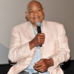 George Foreman smiling at a public event in a suit