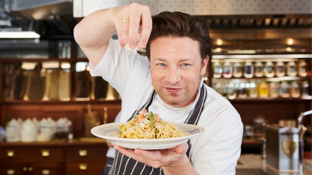 Jamie Oliver cooking on set during a TV show, preparing a meal on-camera