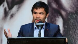 Manny Pacquiao smiling in a suit during a press conference in Manila.