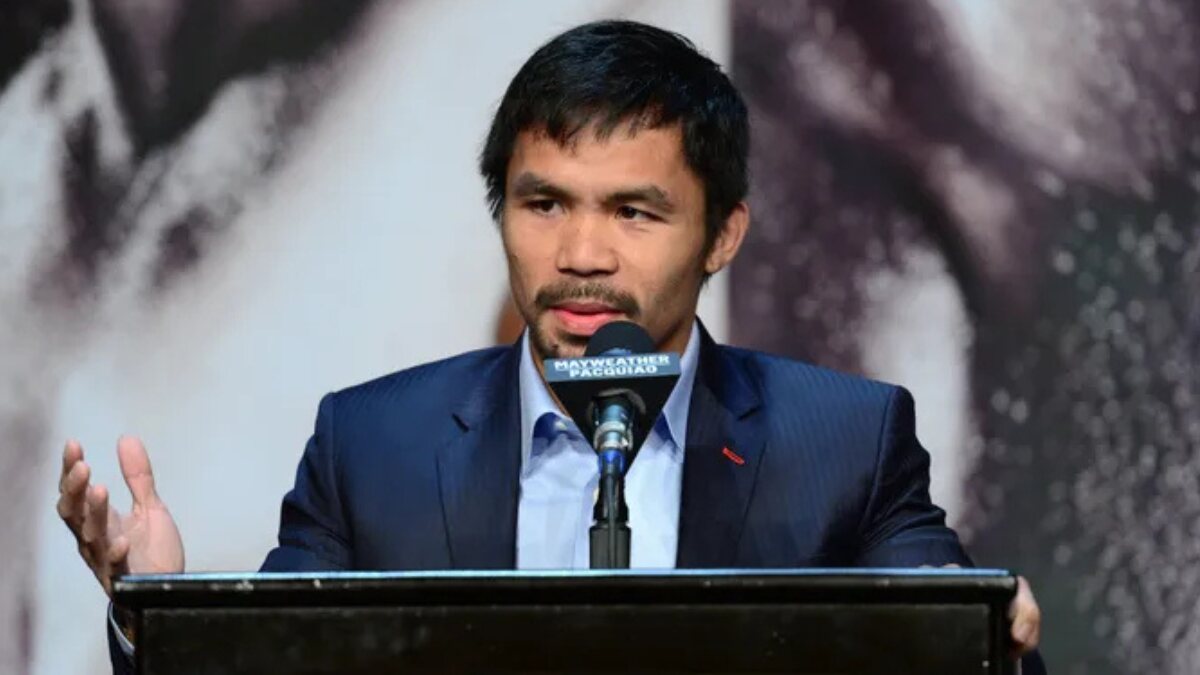 Manny Pacquiao smiling in a suit during a press conference in Manila.