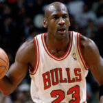 Michael Jordan wearing a Chicago Bulls jersey, mid-air during a slam dunk