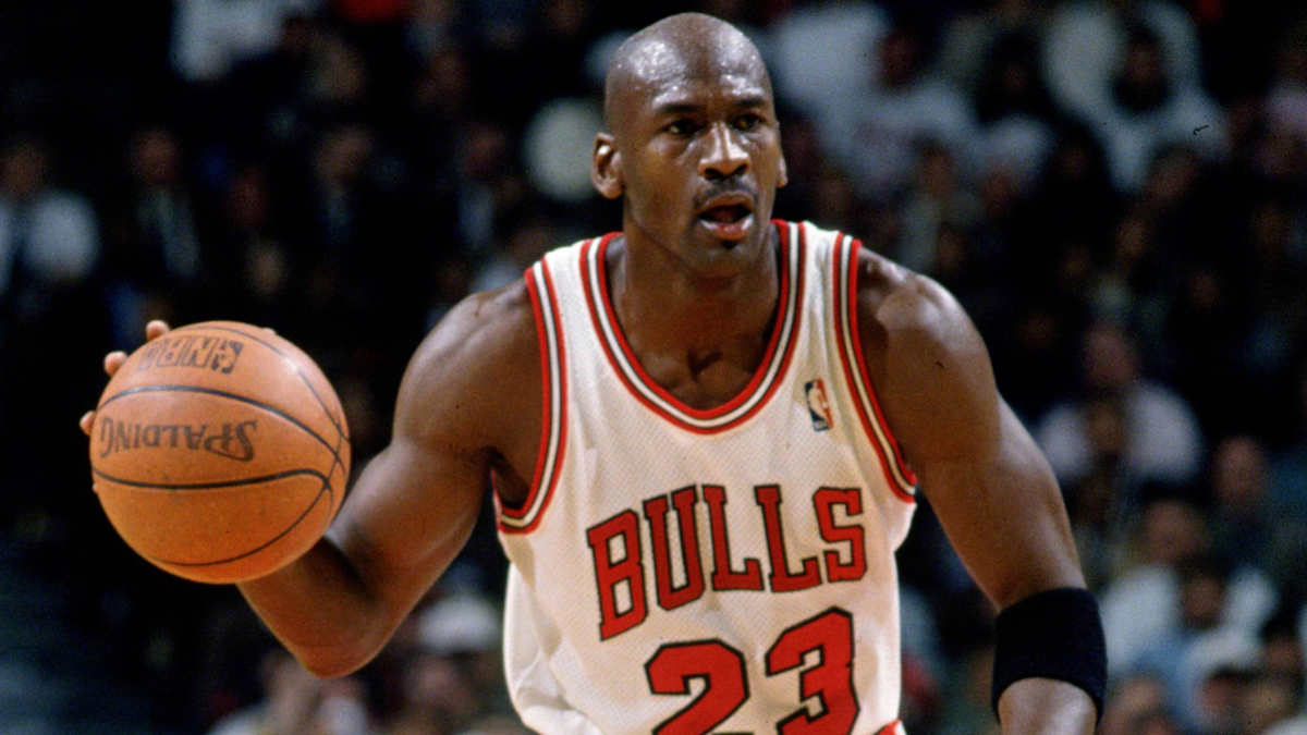 Michael Jordan wearing a Chicago Bulls jersey, mid-air during a slam dunk