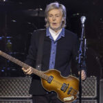 Paul McCartney performing live on stage with guitar during a concert