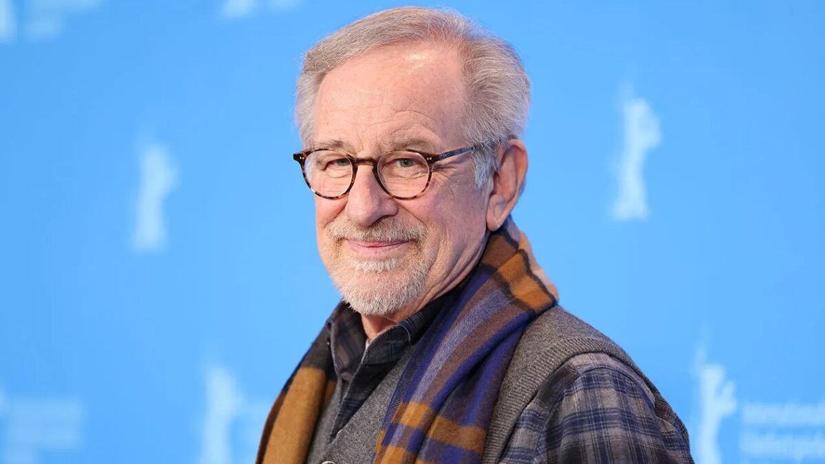Steven Spielberg, legendary film director and producer, wearing glasses and smiling at a red carpet event.