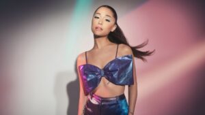 Ariana Grande posing in a REM Beauty photo shoot, wearing futuristic makeup and styled in soft-glam, space-inspired fashion to reflect the brand’s aesthetic.