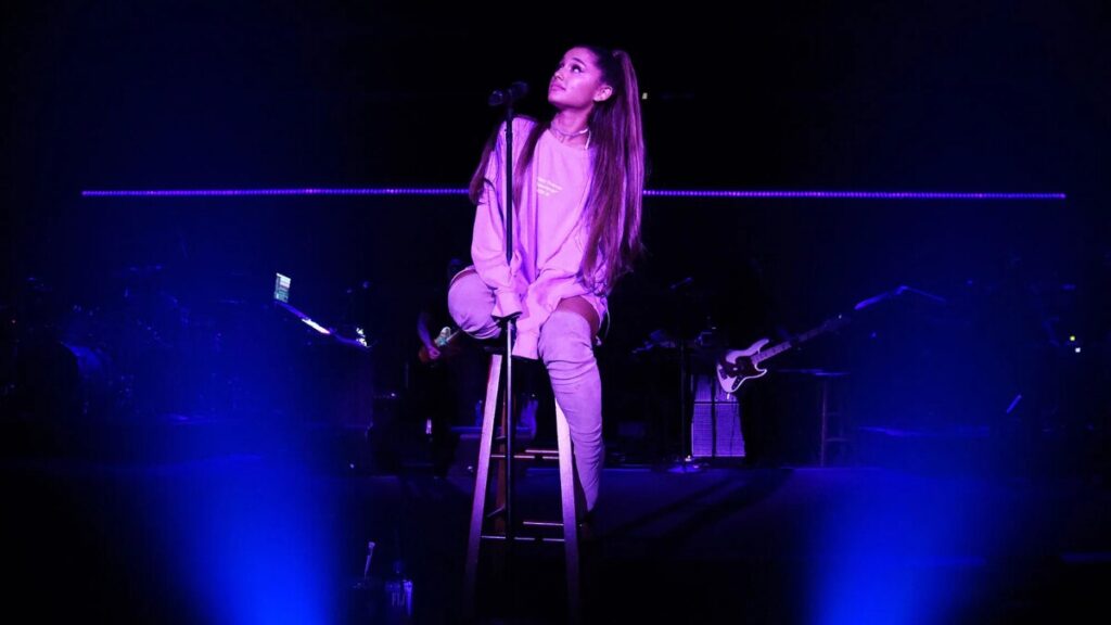 Ariana Grande performing live on stage during her 2025 tour, surrounded by fans and elaborate LED visuals — capturing the Ariana Effect and her influence on pop concert culture.