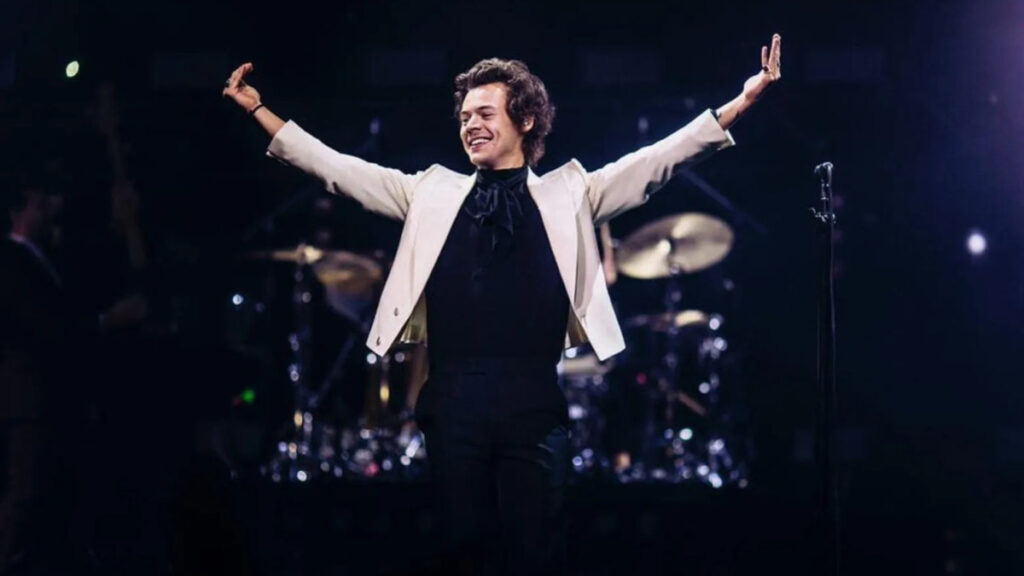 Harry Styles standing on stage during a sold-out concert, representing his rise among the music elite alongside top global artists.