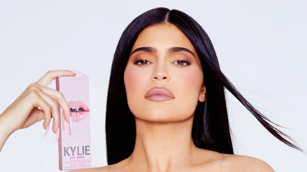 Kylie Jenner applying her signature Lip Kit from Kylie Cosmetics, showcasing the iconic matte finish that launched her beauty empire.