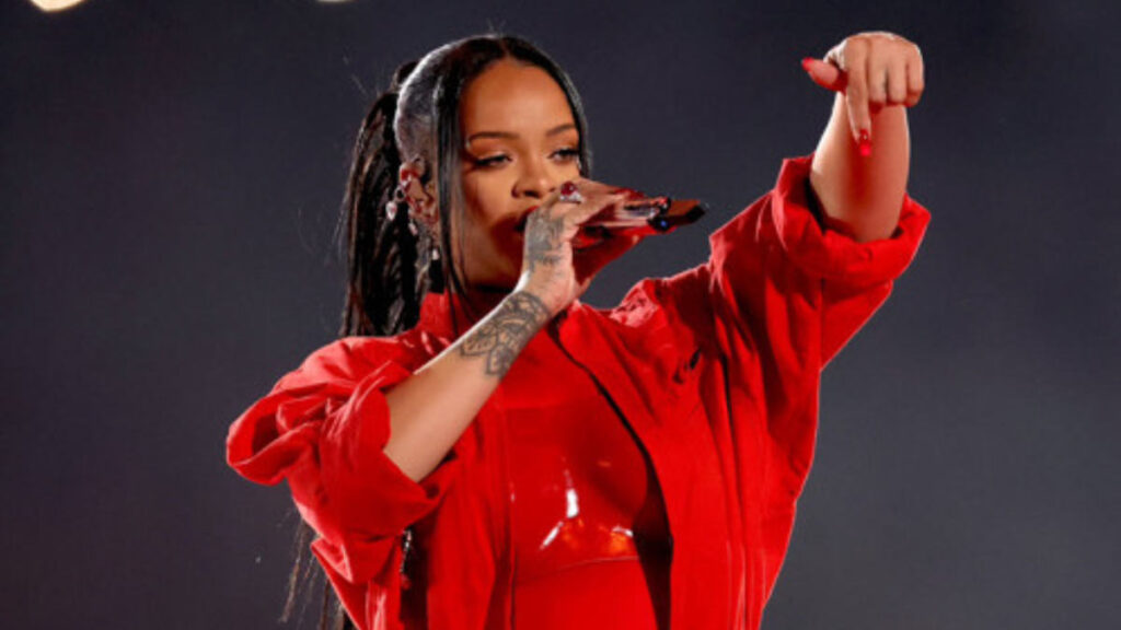 Rihanna performs at the Super Bowl halftime show in a red outfit while pregnant, delivering a high-energy set atop a suspended stage in 2023.
